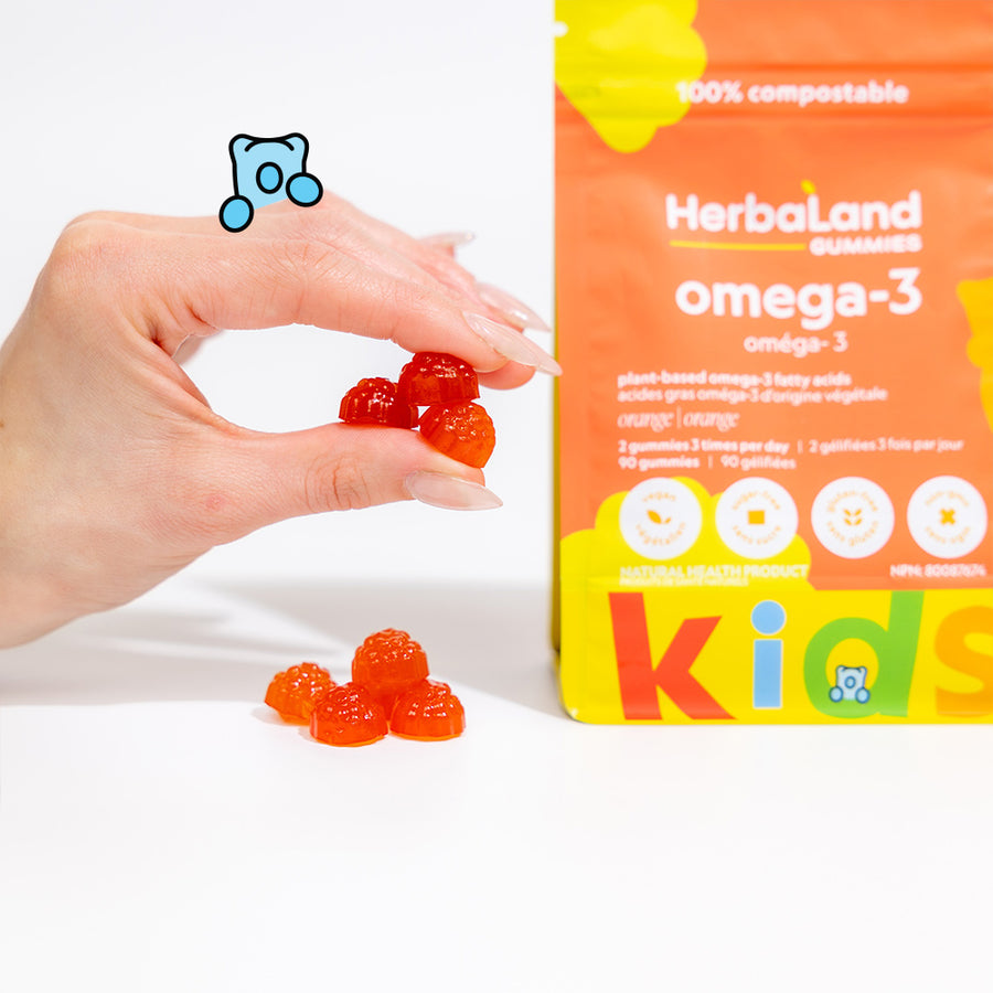 Person holding herbaland gummies with omega-3 pouch for kids to fulfill kid's needs with orange flavor