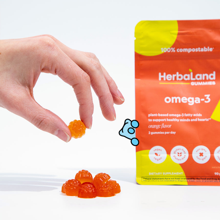 A person hodling herbaland gummies with a pouch of omega-3 gummies for adults with orange flavor at the back