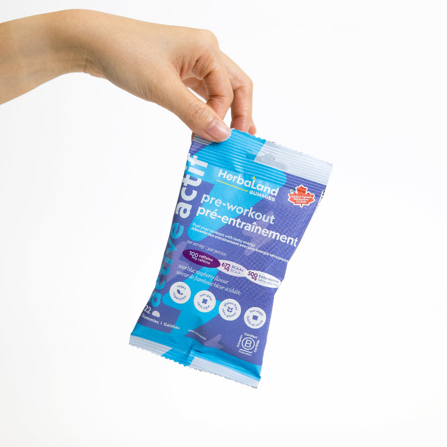 Hand holding a Herballand pre-workout supplement packet against a white background