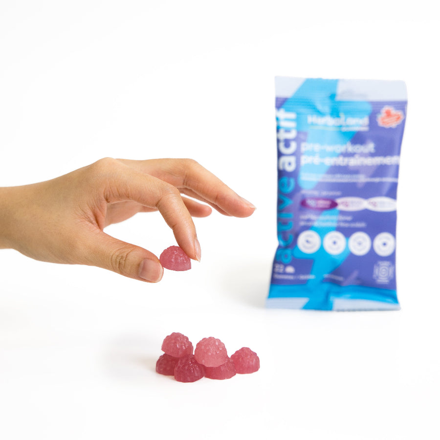 Hand holding a pink gummy next to a blue and white package on a white background
