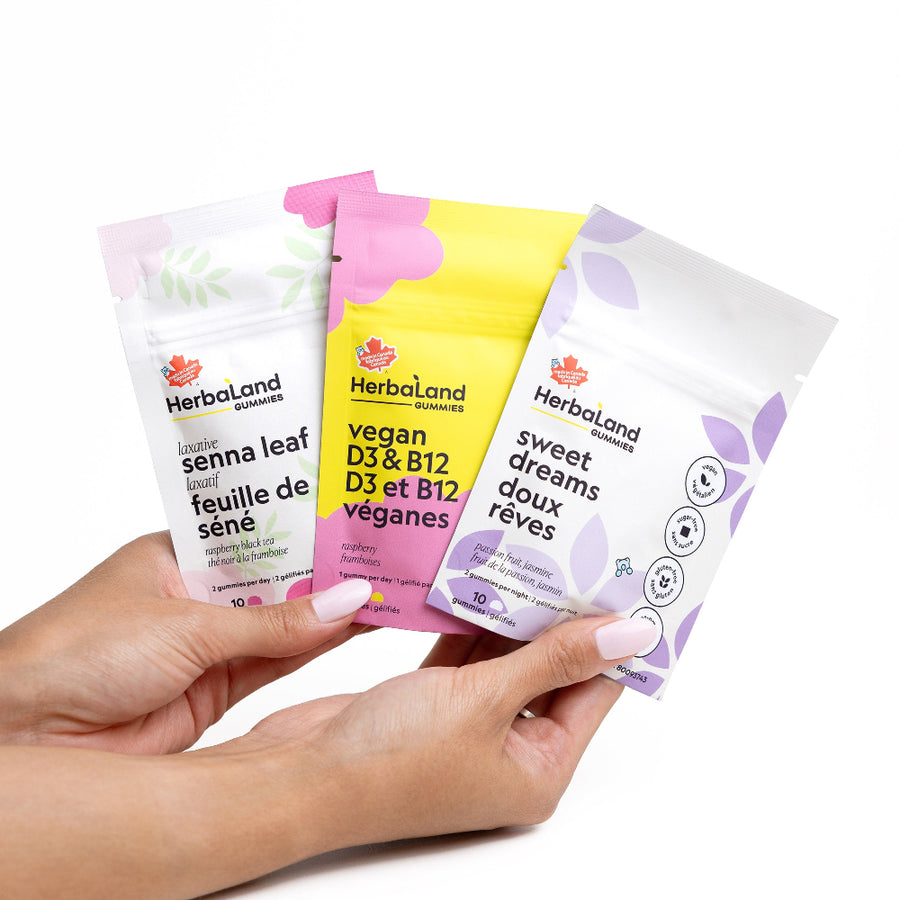 Hand holding three Herbaland supplement packages on a white background