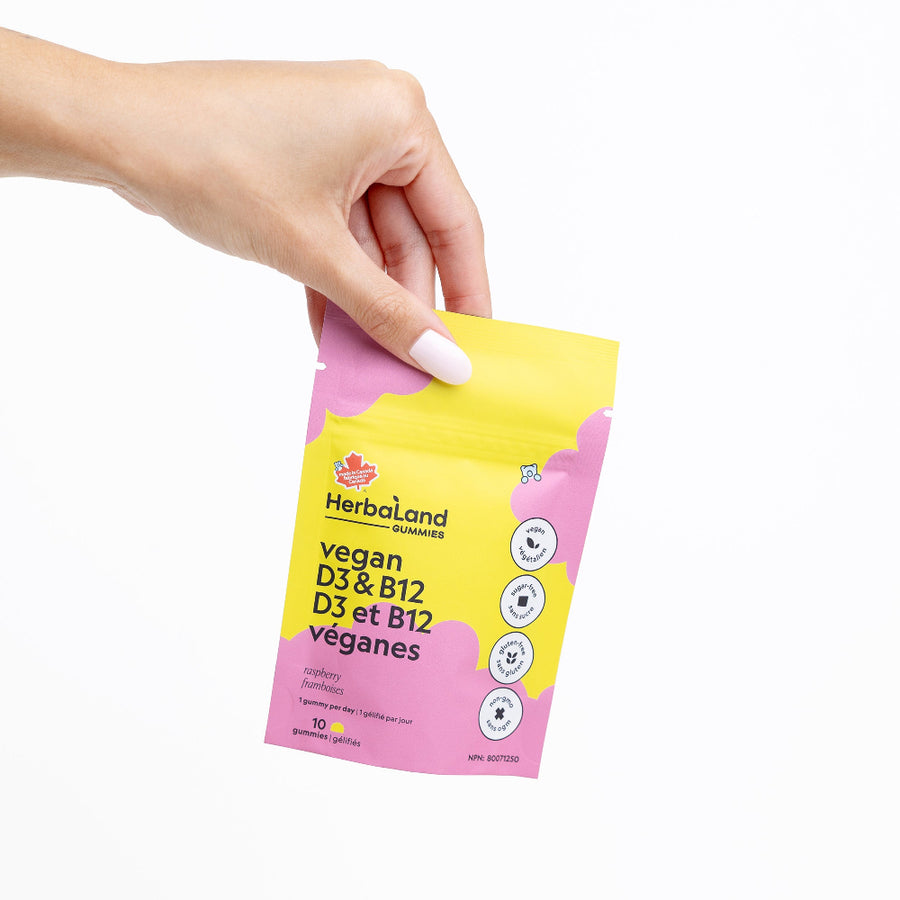 Hand holding a Herballand vegan D3 & B12 supplement packet on a white background