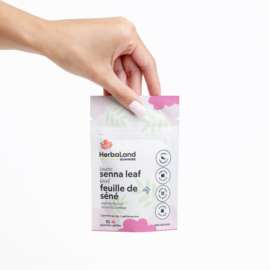 Hand holding a Herbaland senna leaf package against a white background