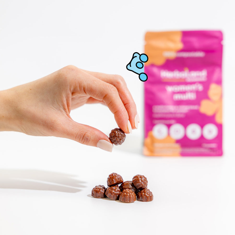 Person holding herbaland gummies with a pouch of women's multi to help to get vitamins and minerals for women with raspberry peach flavor