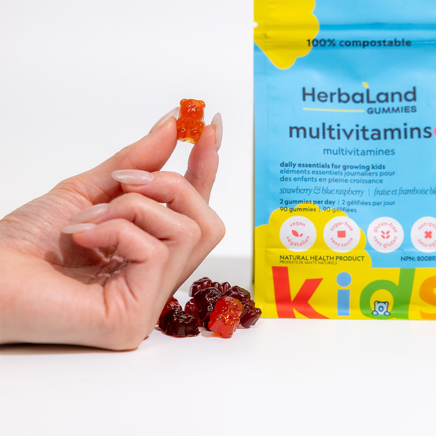 Person holding herbaland gummy bear with a pouch of herbaland gummies multivitamins to help get daily essentials for growing kids with strawberry and blue raspberry flavor 